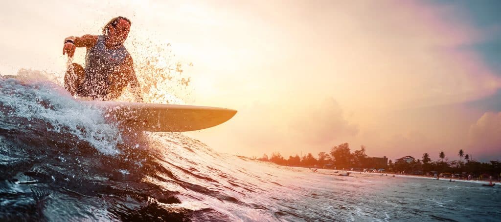Surfer rides the ocean wave in sunset