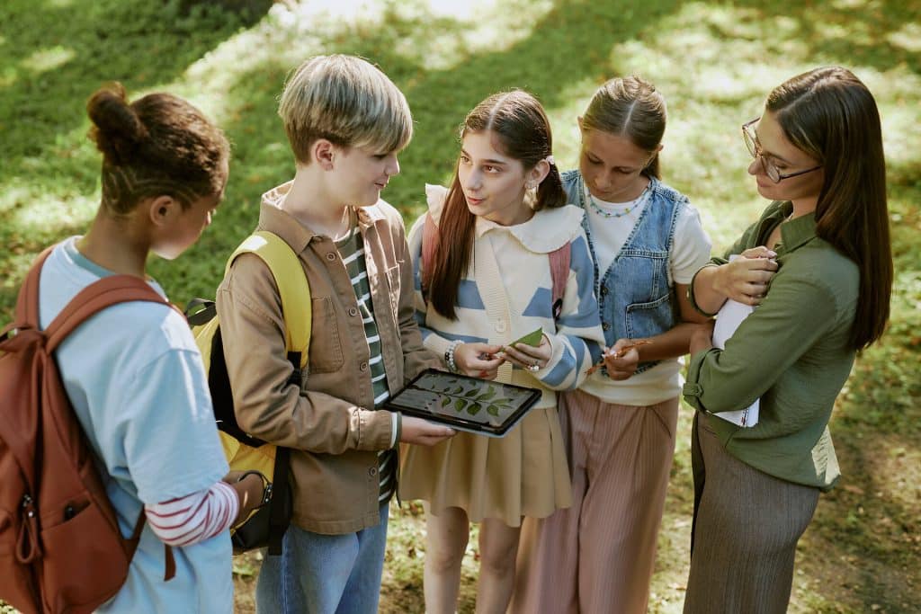 Teenager und Lehrerin mit Tablet im Freien analysieren Blätter