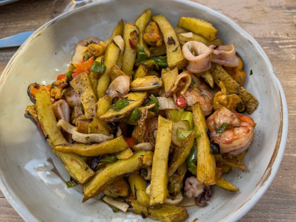 Traditional food from Mallorca: fried potatoes with seafood and green onions, top view