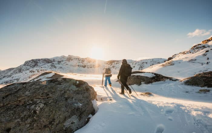 Two mountaineer hiking to peak mountain on snow field at sunset