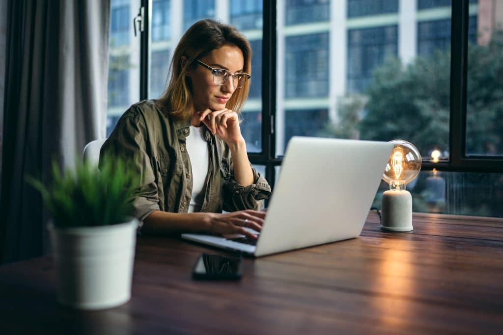 Young woman working with a laptop. Female freelancer connecting to internet via computer. Blogger or journalist writing new article.