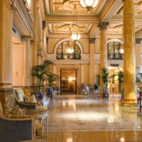 Stilvolle Hotellobby von Grand Hotel im Historischen Stil mit Marmorsäulen und Palmen.