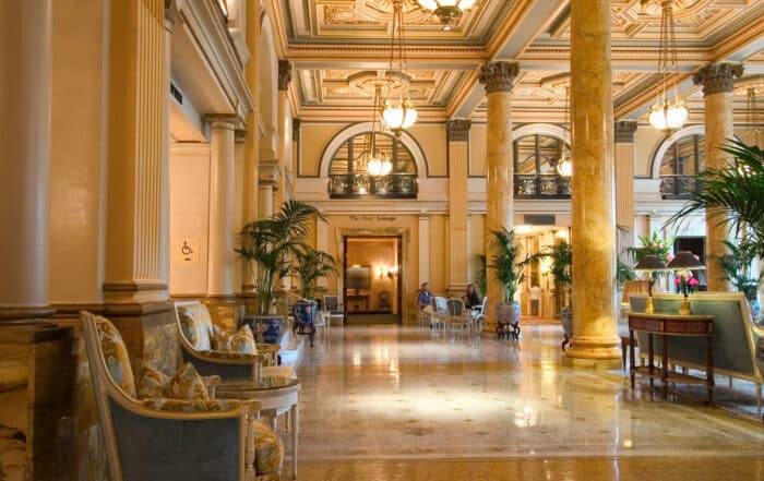 Stilvolle Hotellobby von Grand Hotel im Historischen Stil mit Marmorsäulen und Palmen.