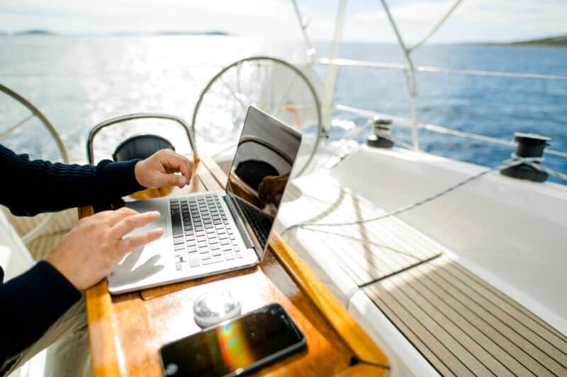 Mann arbeitet auf Laptop auf einem Seegelboot
