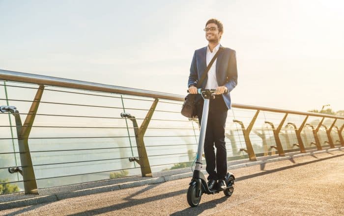 Mann fährt mit dem Scooter über die Brücke