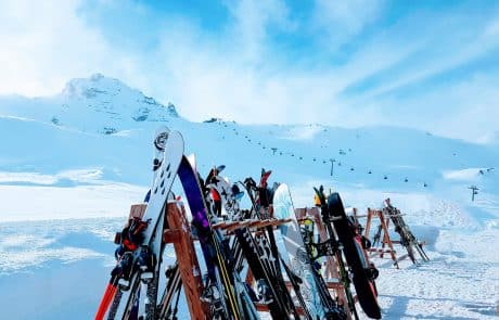 Skifahren: Bunte Ski und Snowboards an Ständer angelehnt vor Gipfellift