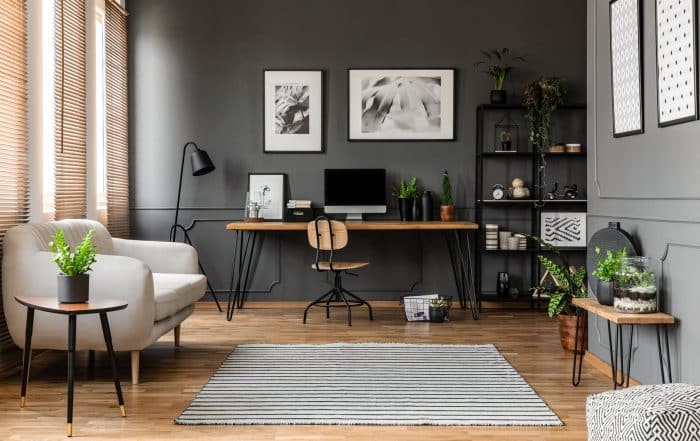 wohnliche Home Office im Wohnzimmer vor grauer Wand mit Bildern