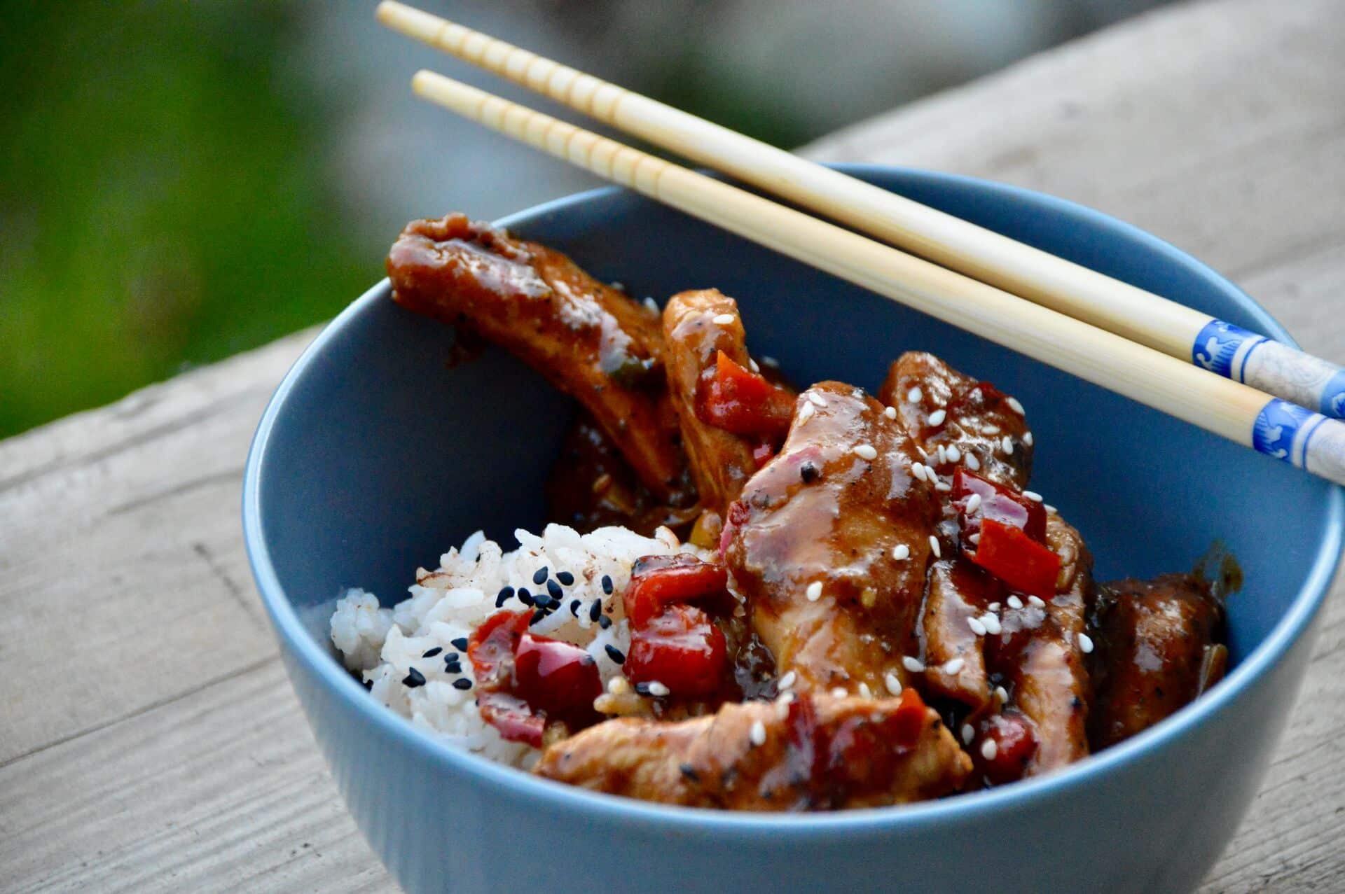 Sichuan-Chicken mit Reis in einer Schale mit Stäbchen